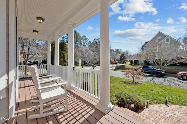 wooden terrace featuring a porch and a yard