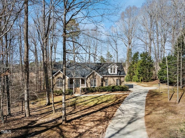 cape cod-style house featuring driveway and a front yard