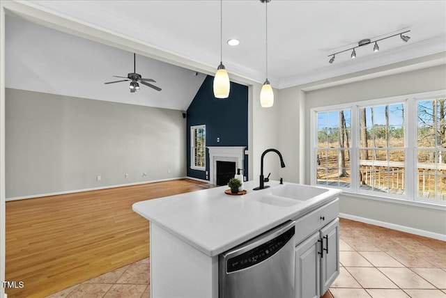 kitchen featuring light tile patterned flooring, a fireplace, a sink, pendant lighting, and stainless steel dishwasher