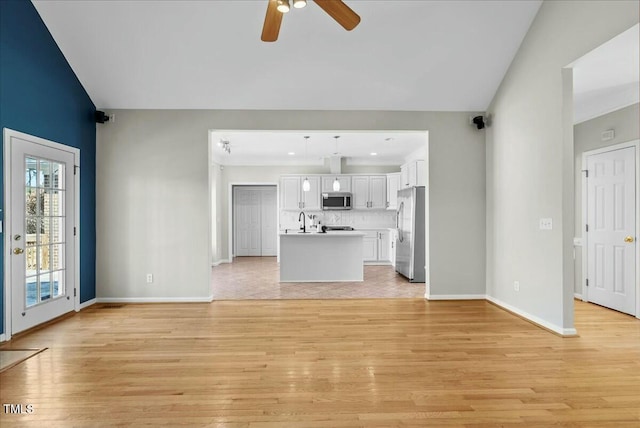 unfurnished living room with lofted ceiling, light wood-style flooring, and baseboards