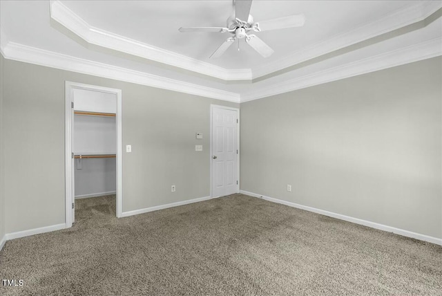 unfurnished bedroom featuring a tray ceiling, carpet floors, baseboards, and crown molding