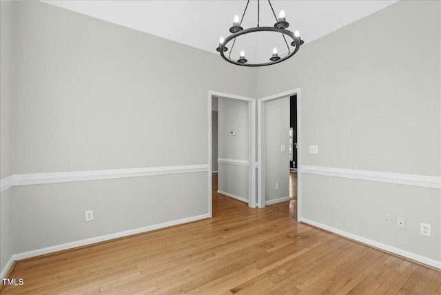 unfurnished dining area with light wood-style flooring, a notable chandelier, and baseboards