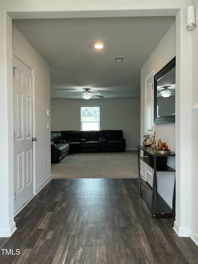 living area featuring visible vents, baseboards, ceiling fan, and dark wood-style flooring