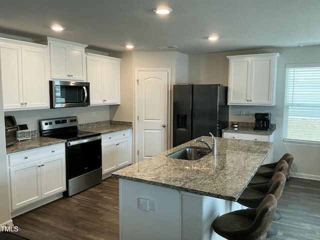 kitchen with a sink, dark wood-type flooring, appliances with stainless steel finishes, and white cabinetry