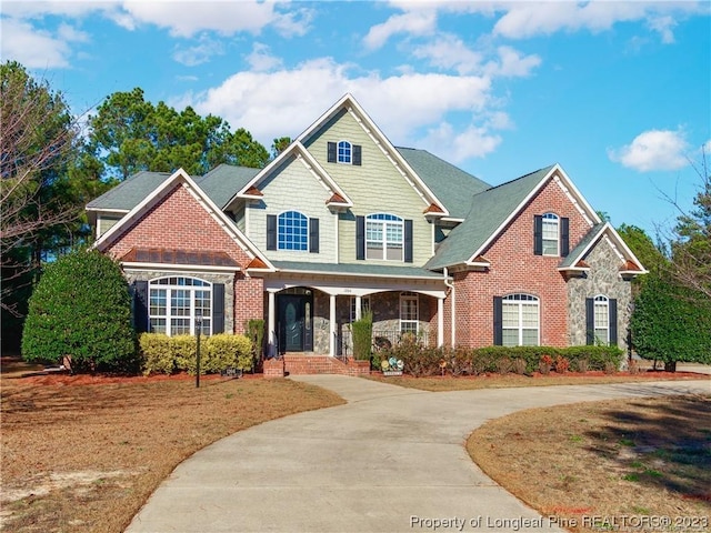 craftsman inspired home with concrete driveway, brick siding, and stone siding