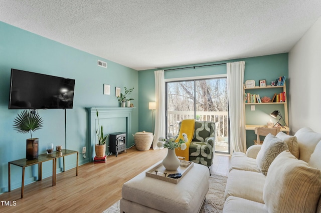 living room featuring visible vents, a textured ceiling, and wood finished floors