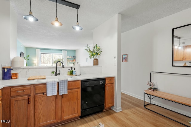 kitchen with black dishwasher, light wood-style flooring, brown cabinetry, and light countertops