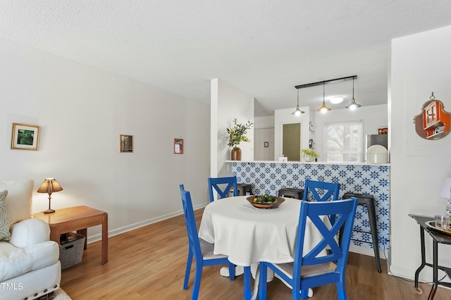 dining area with wood finished floors, baseboards, and a textured ceiling