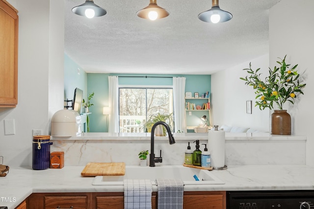 kitchen with dishwasher, light countertops, brown cabinetry, a textured ceiling, and a sink