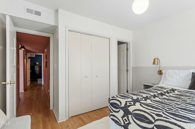 bedroom with visible vents, a closet, and light wood finished floors