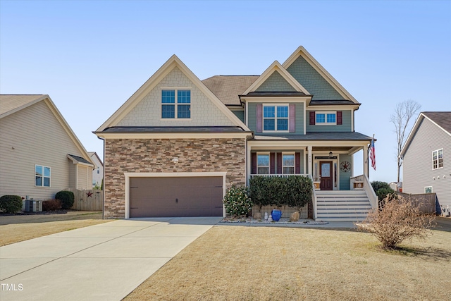 craftsman-style house featuring a porch, concrete driveway, central AC, stone siding, and an attached garage