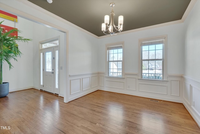 interior space with a chandelier, visible vents, light wood-style floors, and ornamental molding