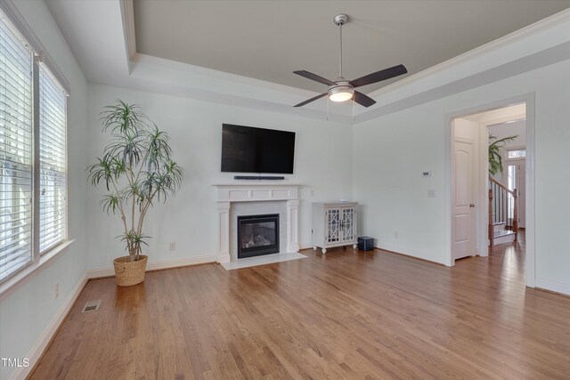 unfurnished living room with visible vents, a raised ceiling, wood finished floors, and a fireplace with flush hearth