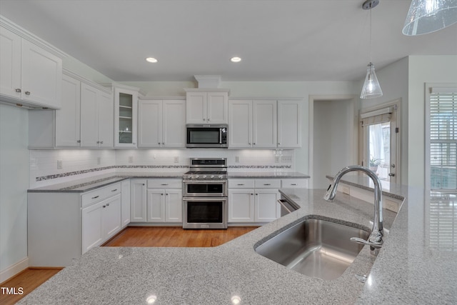 kitchen featuring a sink, light stone countertops, white cabinetry, and stainless steel appliances