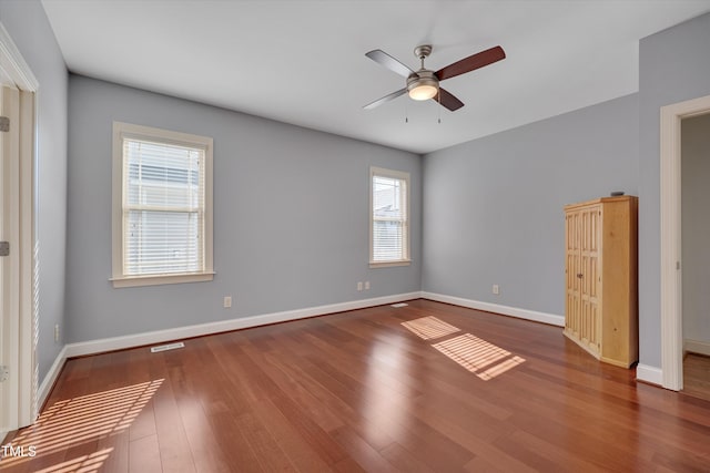 spare room featuring visible vents, a ceiling fan, baseboards, and wood finished floors