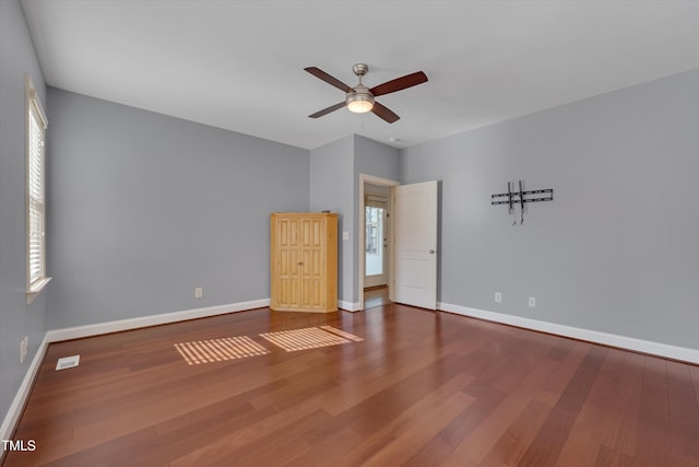 unfurnished bedroom featuring a ceiling fan, visible vents, wood finished floors, and baseboards