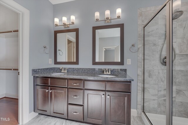 full bathroom featuring a walk in closet, a shower stall, and a sink