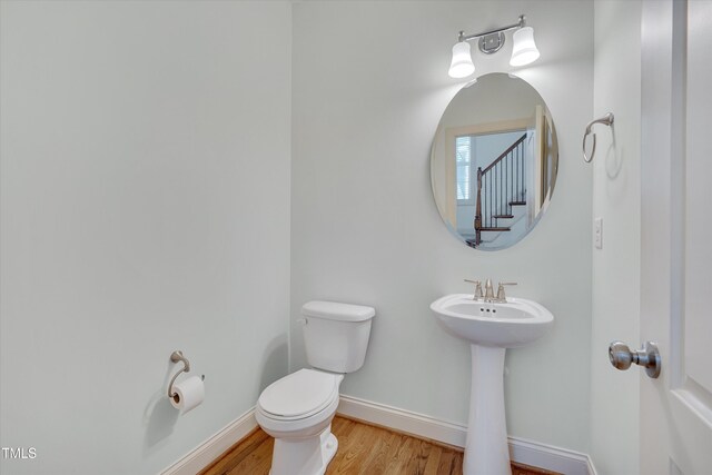 half bath featuring toilet, baseboards, and wood finished floors