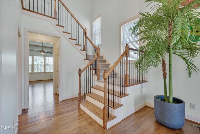 staircase with baseboards, a high ceiling, and wood finished floors