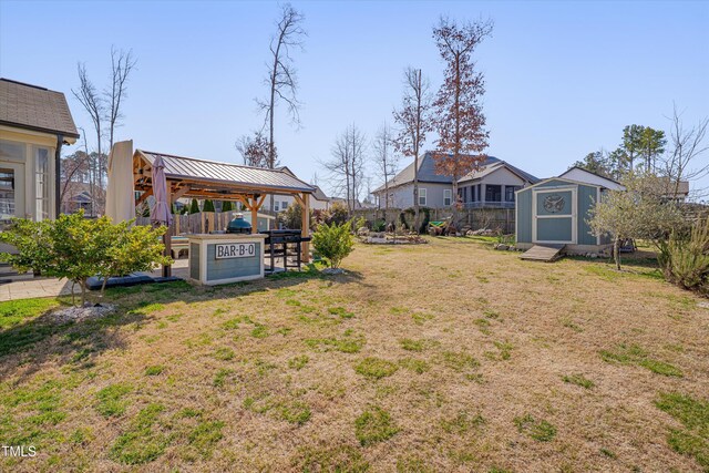 view of yard with a gazebo, a storage unit, a fenced backyard, and an outdoor structure