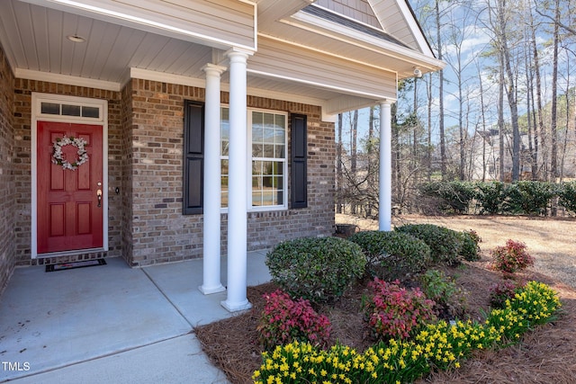 property entrance featuring brick siding and a porch