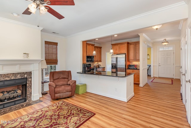 kitchen with a peninsula, stainless steel refrigerator with ice dispenser, black microwave, dark countertops, and brown cabinets