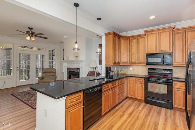 kitchen with a fireplace, a sink, decorative backsplash, black appliances, and open floor plan