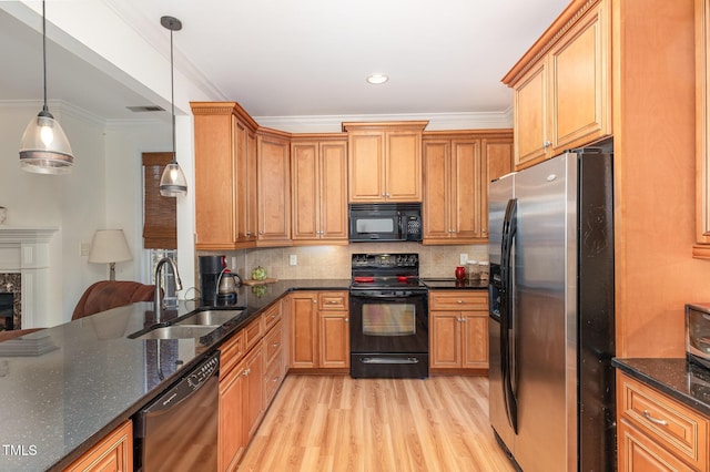 kitchen with light wood-style flooring, ornamental molding, decorative backsplash, black appliances, and a sink