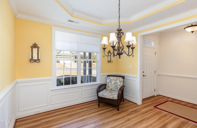 sitting room featuring a wainscoted wall, crown molding, light wood-style flooring, and visible vents