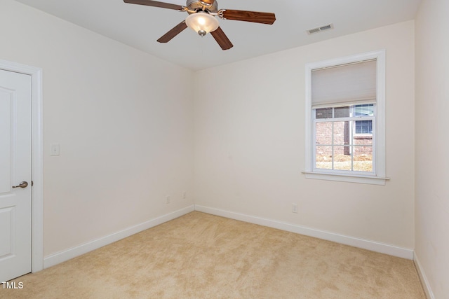 spare room featuring light carpet, visible vents, ceiling fan, and baseboards