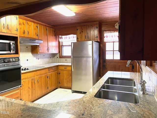 kitchen with a sink, black appliances, wood ceiling, under cabinet range hood, and tasteful backsplash