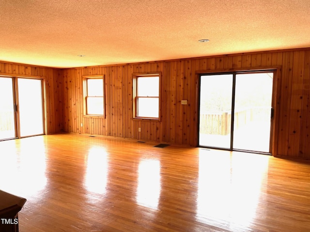 unfurnished living room with light wood-style floors, a wealth of natural light, and a textured ceiling