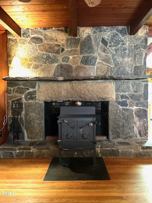 interior details with a stone fireplace, a wood stove, and wood finished floors