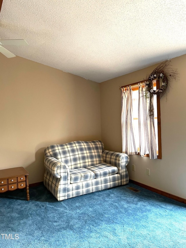 living room featuring baseboards, a textured ceiling, a ceiling fan, and carpet floors