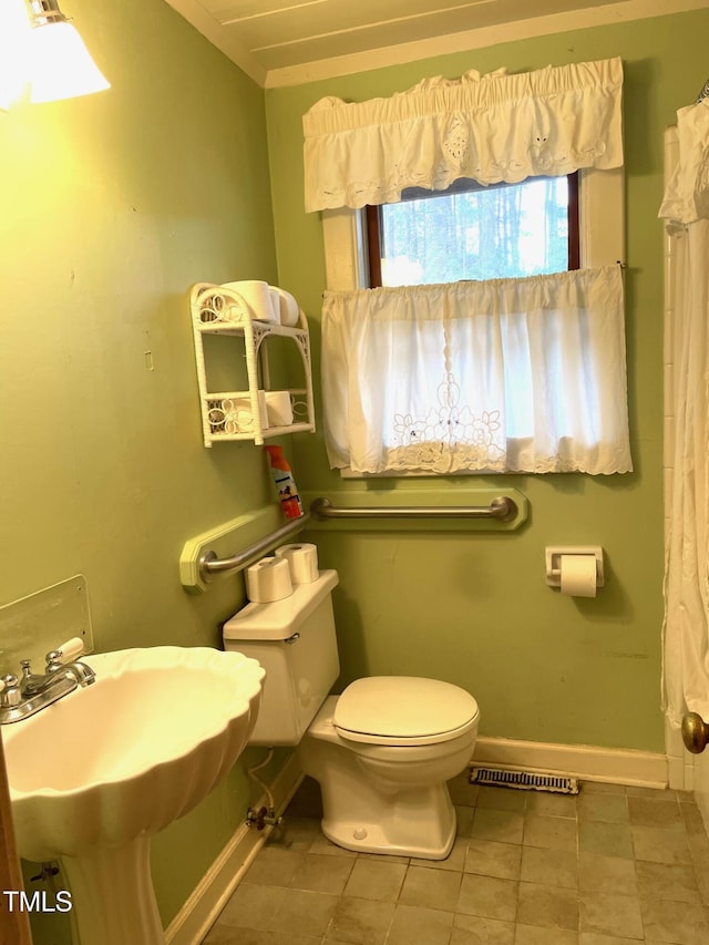 full bath with a sink, curtained shower, baseboards, and toilet