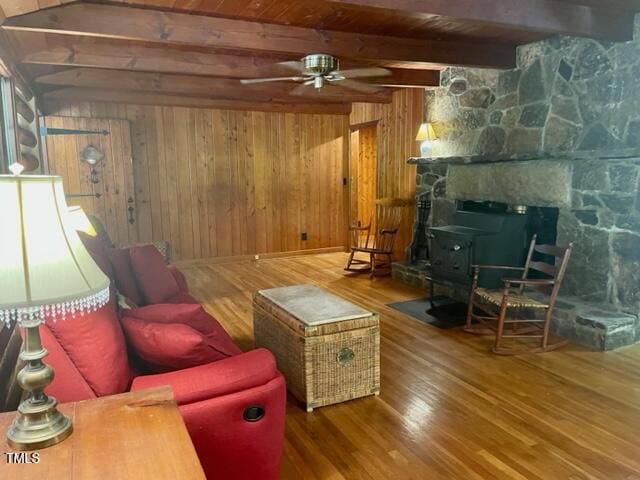 182 Tree Cutters, Sanford, NC 27332 - living room with wood finished floors, a ceiling fan, wooden walls, wood ceiling with exposed beams, and a wood stove