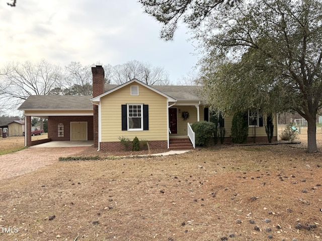 ranch-style home with an attached carport, driveway, a chimney, and roof with shingles