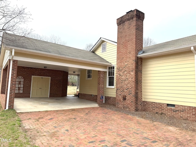exterior space with a carport, roof with shingles, and a chimney