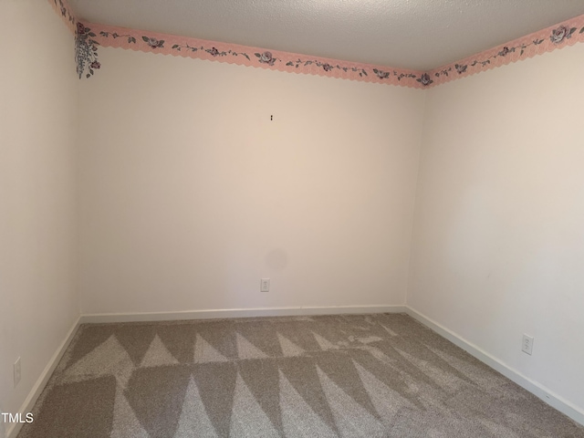 unfurnished room featuring baseboards, carpet, and a textured ceiling