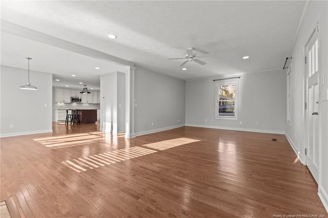 unfurnished living room with a ceiling fan, a textured ceiling, wood finished floors, recessed lighting, and baseboards