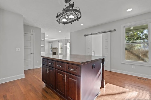 kitchen featuring visible vents, baseboards, a barn door, and wood finished floors