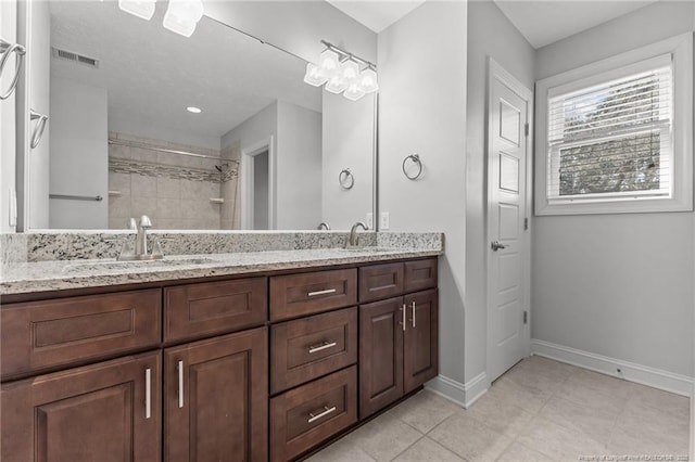 full bath with a tile shower, visible vents, baseboards, and a sink