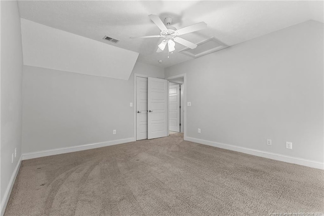 unfurnished bedroom featuring carpet, baseboards, visible vents, attic access, and lofted ceiling