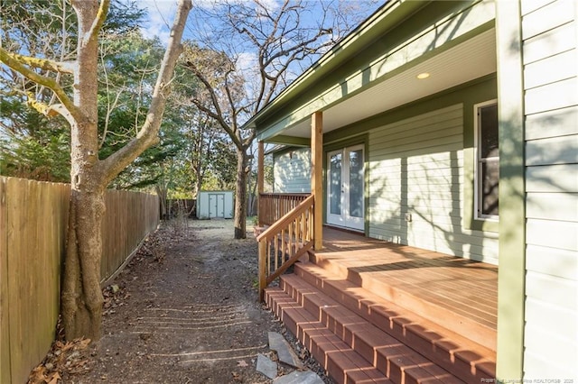 wooden deck with an outbuilding, french doors, a storage shed, and a fenced backyard