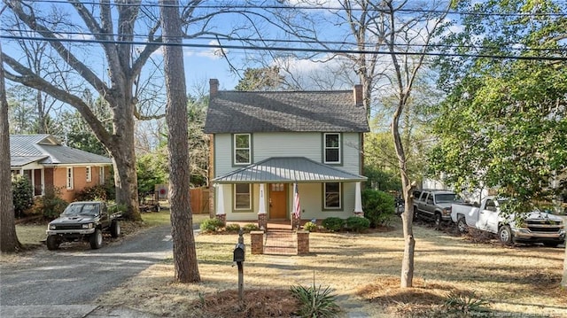 view of front of home with a chimney, a porch, driveway, and fence