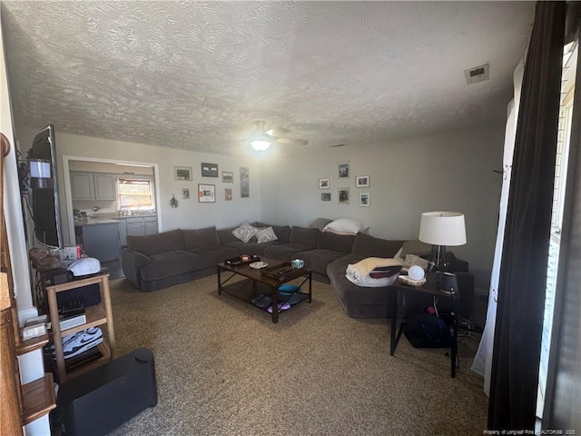 living area featuring visible vents, carpet, and a textured ceiling