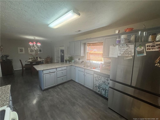 kitchen with dark wood finished floors, light countertops, a peninsula, freestanding refrigerator, and a sink