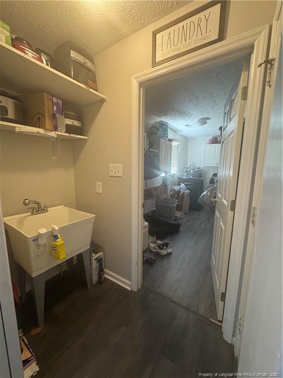 laundry area featuring dark wood finished floors, a textured ceiling, and a sink