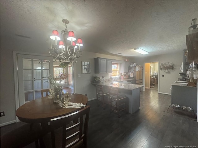 dining room with dark wood finished floors, a notable chandelier, baseboards, and a textured ceiling