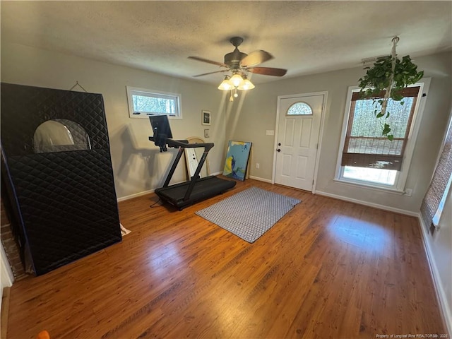 foyer with a textured ceiling, a ceiling fan, baseboards, and wood finished floors